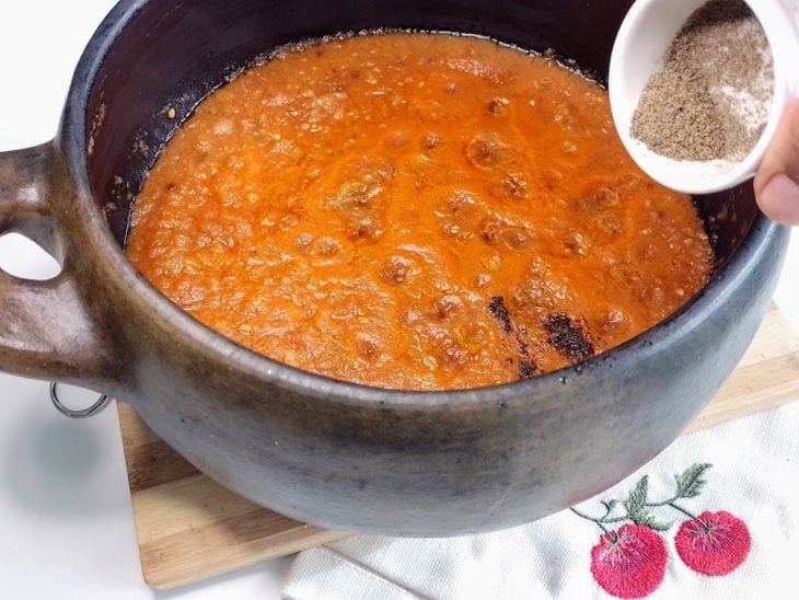 Uma panela contendo molho de tomate sendo temperado.