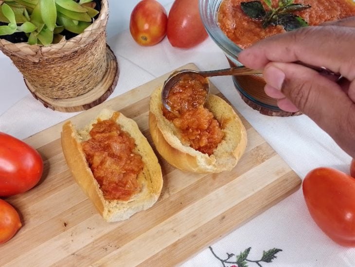 Uma tábua contendo pães sendo recheados com molho de tomate.