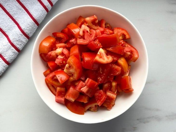 Tigela com tomates picados em pedaços menores.