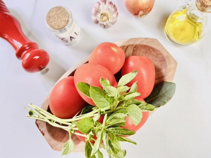 Ingredientes para a receita de molho de tomate caseiro rápido reunidos em uma bancada.