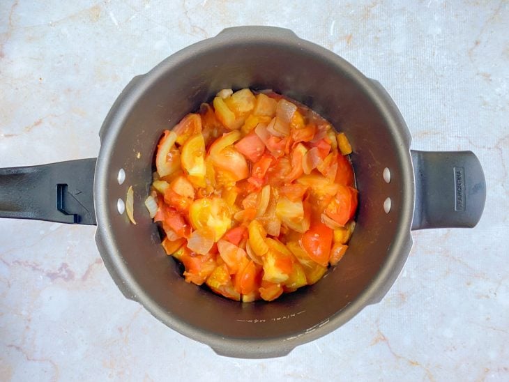 Tomates e alho refogando na panela de pressão.