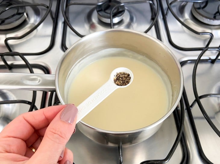 Uma panela com creme branco e pimentas.