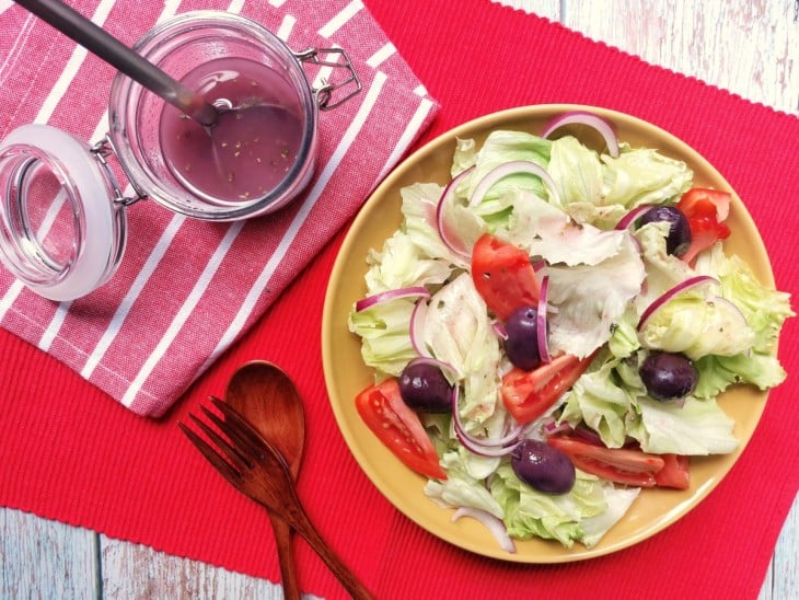 Uma bancada contendo um recipiente com molho italiano e um prato com salada.