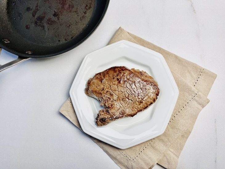 Carne grelhada reservada em um prato branco.
