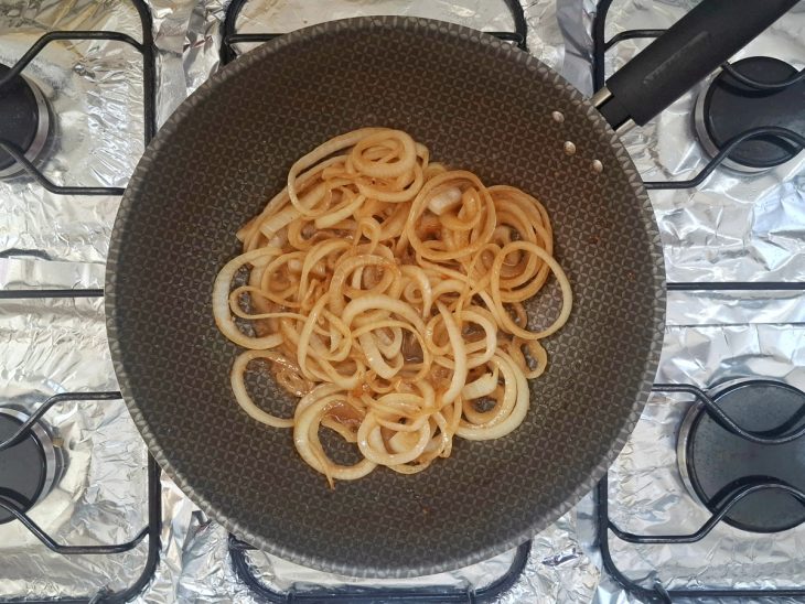 Frigideira ao fogo com as cebolas a dourar.