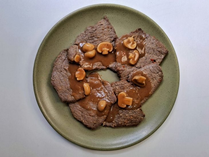 Um prato com o bife e o molho por cima.