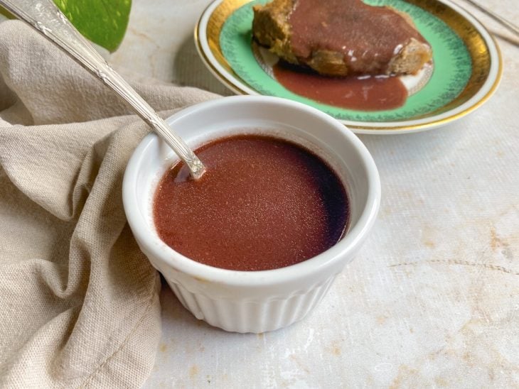 Um prato contendo carne servida com molho madeira simples e um reicpiente com o molho.