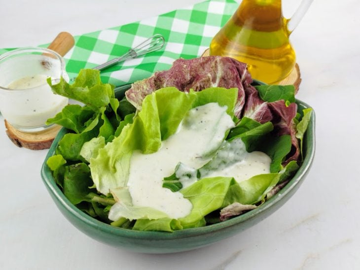 Molho pronto para consumo acompanhando uma salada de folhas verdes.