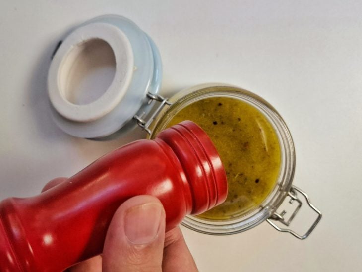 Pimenta sendo adicionada no pote com o molho.