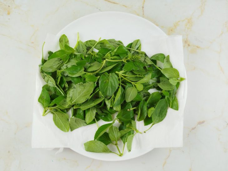 Manjericão seco cuidadosamente sobre papel-toalha.