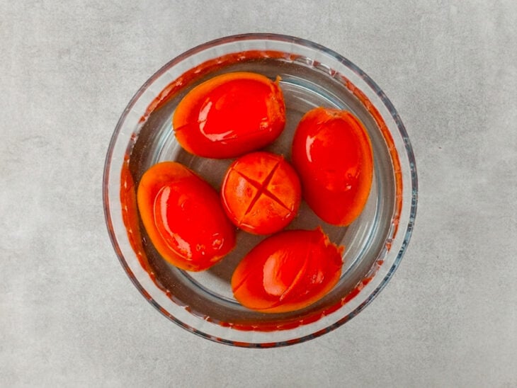 Tomates transferidos da água quente para uma tigela com água fria.