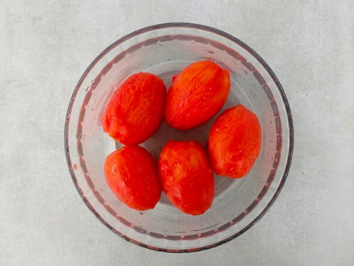 Cascas dos tomates sendo removidas delicadamente após o choque térmico.