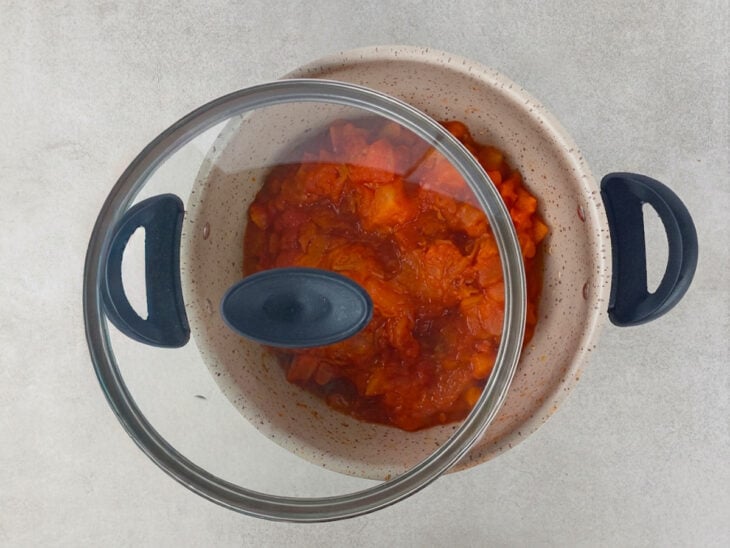 Molho cozinhando parcialmente tampado enquanto reduz naturalmente.