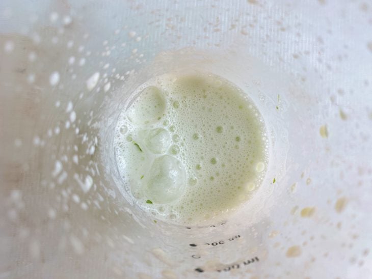 Cheiro-verde, sal e leite batidos em um liquidificador.