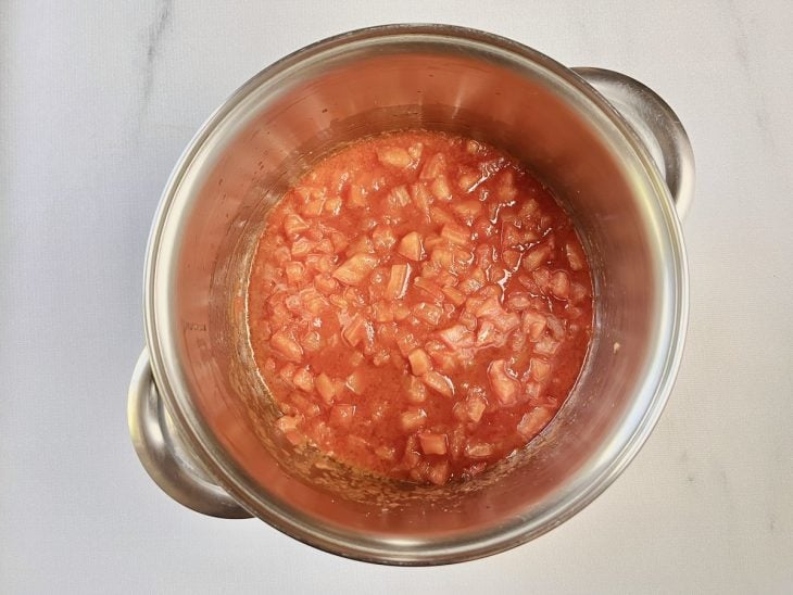 Alho, cebola e tomates refogados em uma panela com azeite de oliva e azeite de dendê.