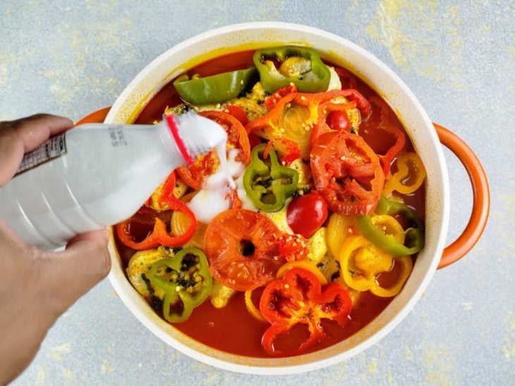 Leite de coco sendo adicionado na panela com a moqueca.