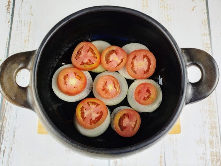 Uma panela com azeite, tomate e cebola.