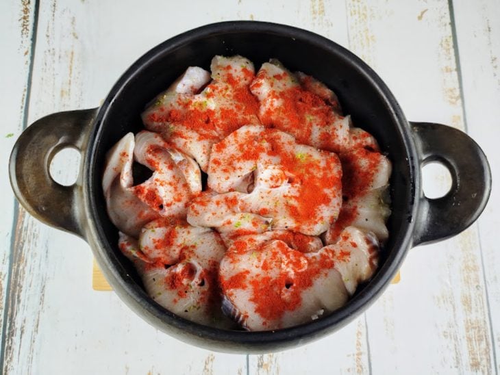 Uma panela com azeite, tomate, cebola, pimentões, cação e temperos.