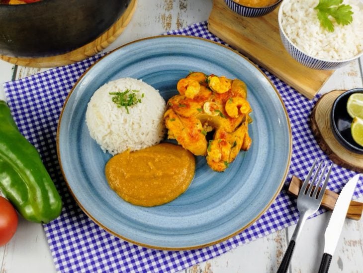 Prato contendo moqueca de cação com camarão e acompanhamentos.