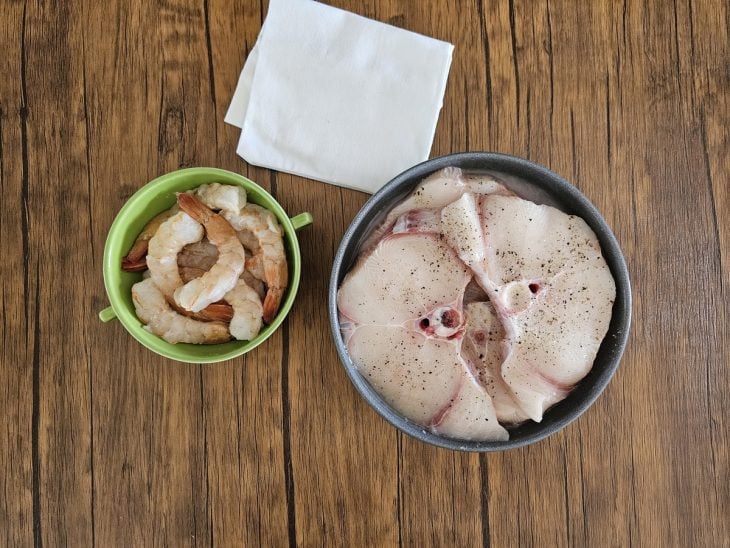 Dois recipientes contendo peixe e camarão temperados.