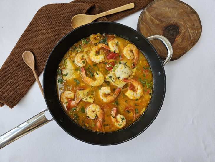 Uma panela contendo moqueca de peixe com camarão.