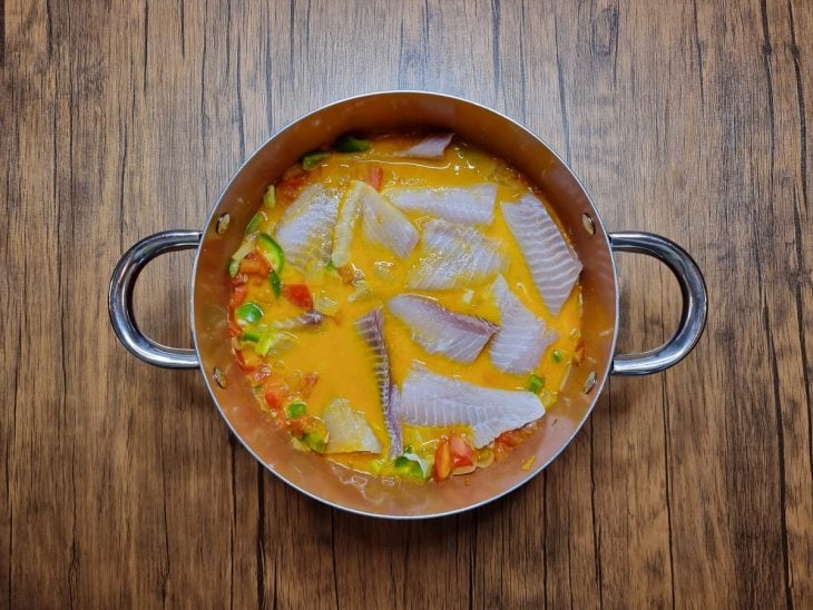 Filés de peixe adicionados à panela com caldo, legumes e temperos.