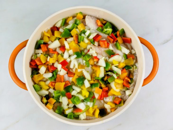 Os legumes cortados em cubo, por cima do peixe.