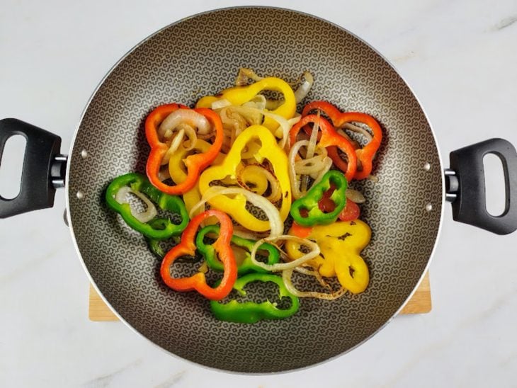 Uma panela com azeite, cebola, pimentões, sal.