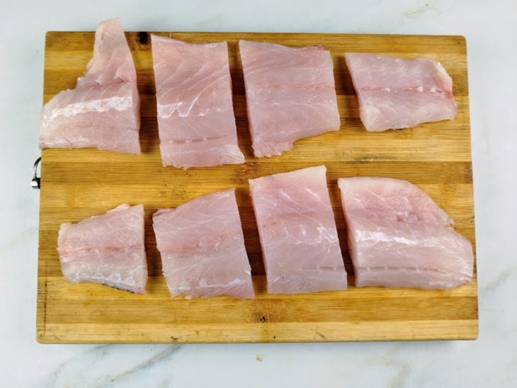 Uma tábua com os peixes cortados.