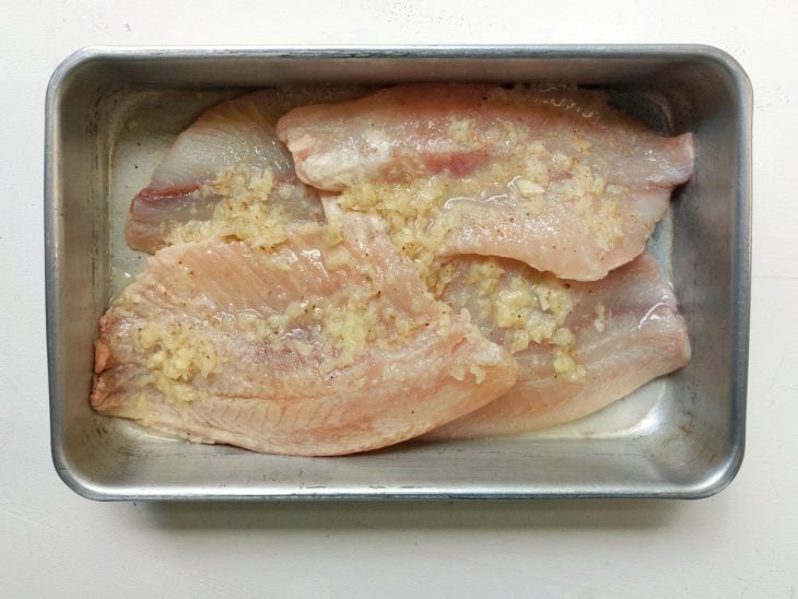 Uma forma contendo filés de peixe temperados.