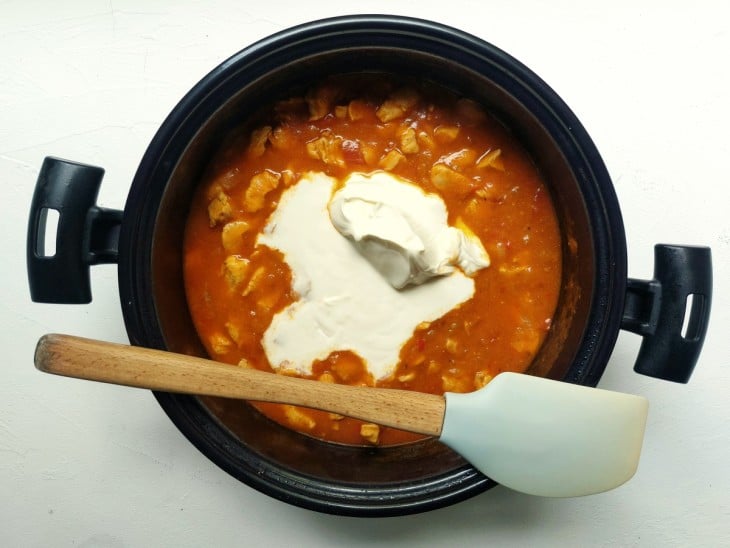 Uma panela contendo molho de tomate, frango e creme de leite.