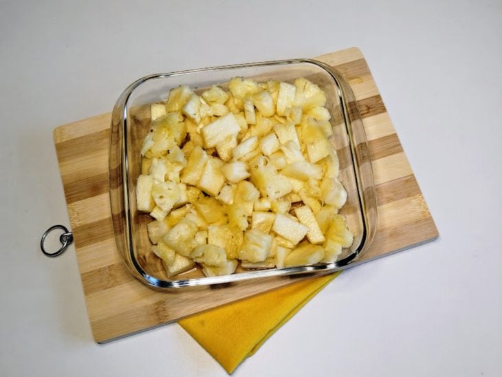 Um recipiente com abacaxi picado.
