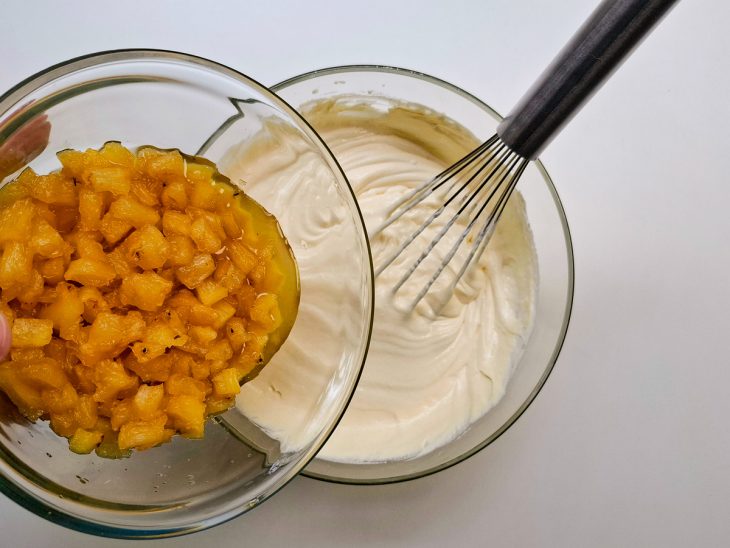 Pedaços de abacaxi adicionados no creme branco.