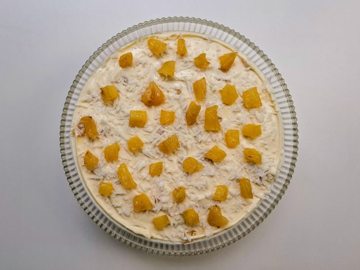 Mousse de abacaxi montado num recipiente de vidro redondo.