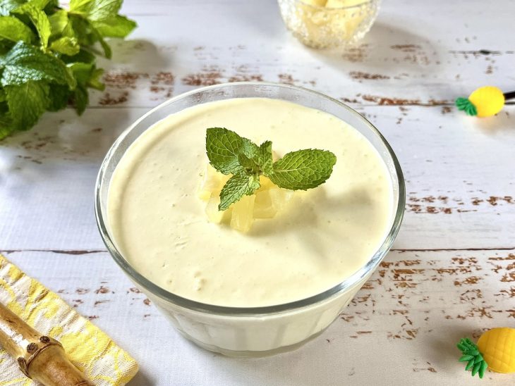 Mousse de abacaxi simples no liquidificador finalizado com pedacinhos da fruta e folhas de hortelã.