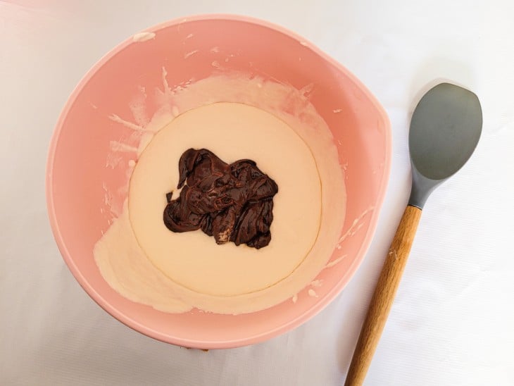 Creme cor de chocolate sendo misturado à creme de cor branca em uma tigela.