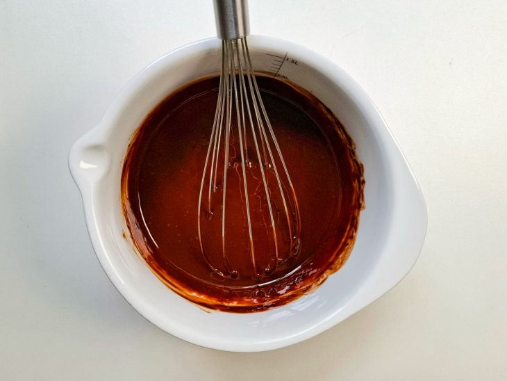 Numa tigela, chocolate derretido em banho-maria.