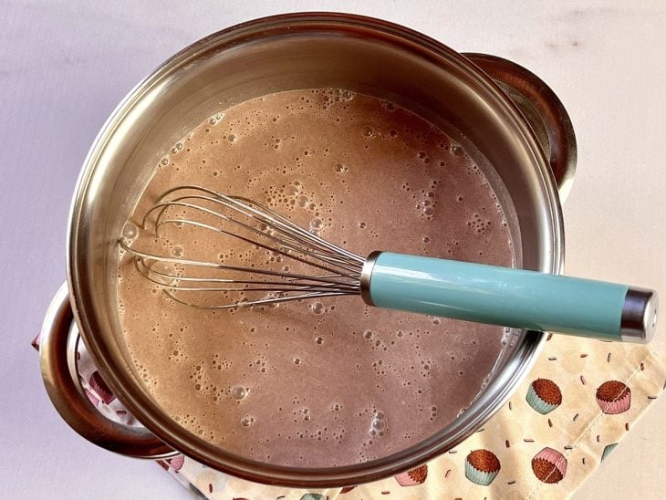 Uma panela contendo a mistura de leite, creme de leite, chocolate em pó, amido de milho e açúcar.