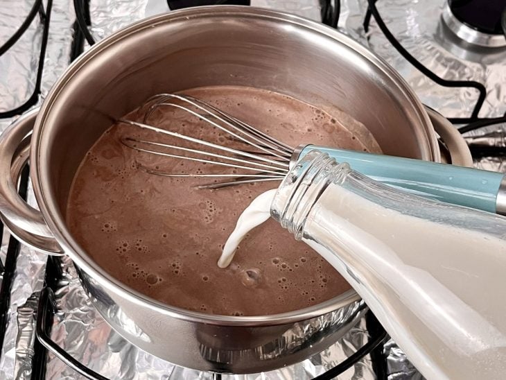 Uma panela contendo a mistura de leite, creme de leite, chocolate em pó, amido de milho e açúcar.