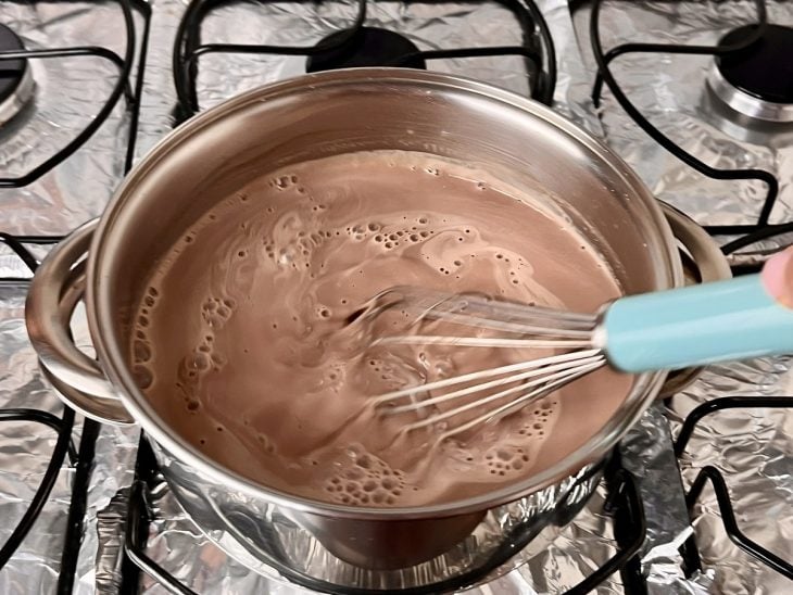 Uma panela contendo a mistura de leite, creme de leite, chocolate em pó, amido de milho e açúcar.