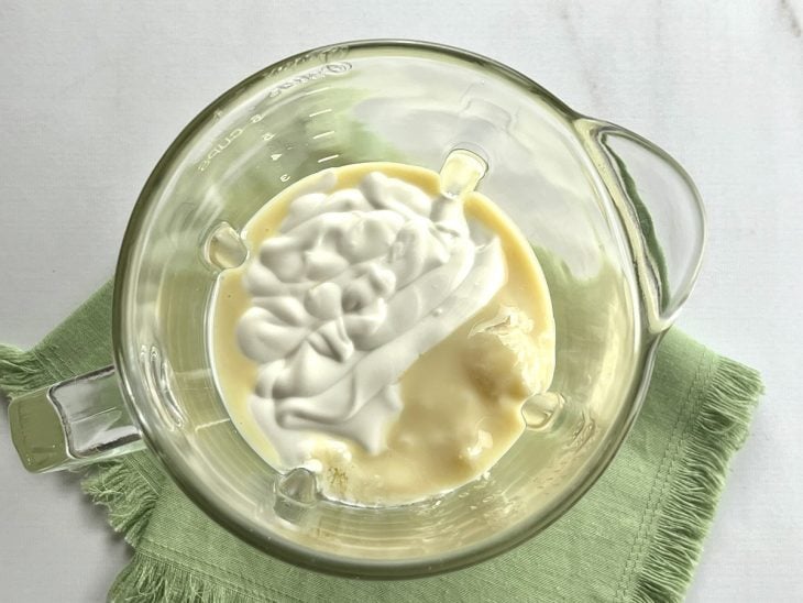 Um liquidificador contendo polpa de cupuaçu, creme de leite e leite condensado.