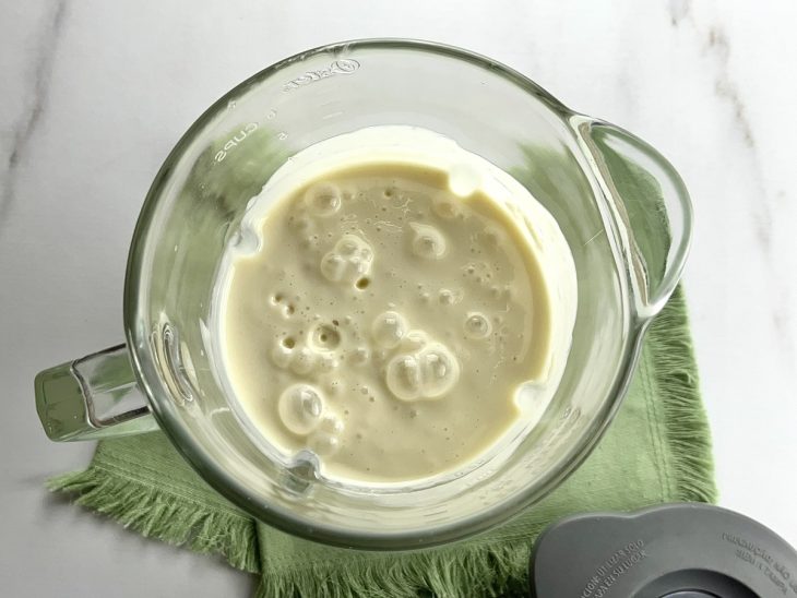 Um liquidificador com a mistura de polpa de cupuaçu, creme de leite e leite condensado.