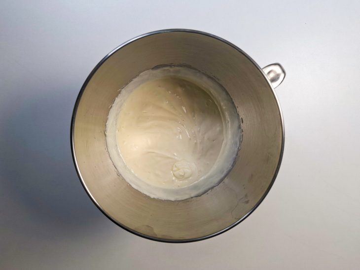 Manteiga e leite condensado sendo batidos na batedeira até formar um creme claro
