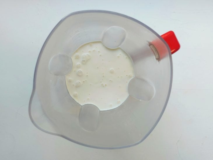Um liquidificador contendo creme de leite e leite condensado.