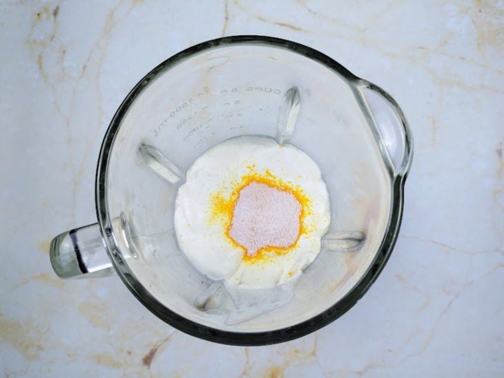 Um liquidificador contendo a mistura de creme de leite, suco em pó e leite condensado.