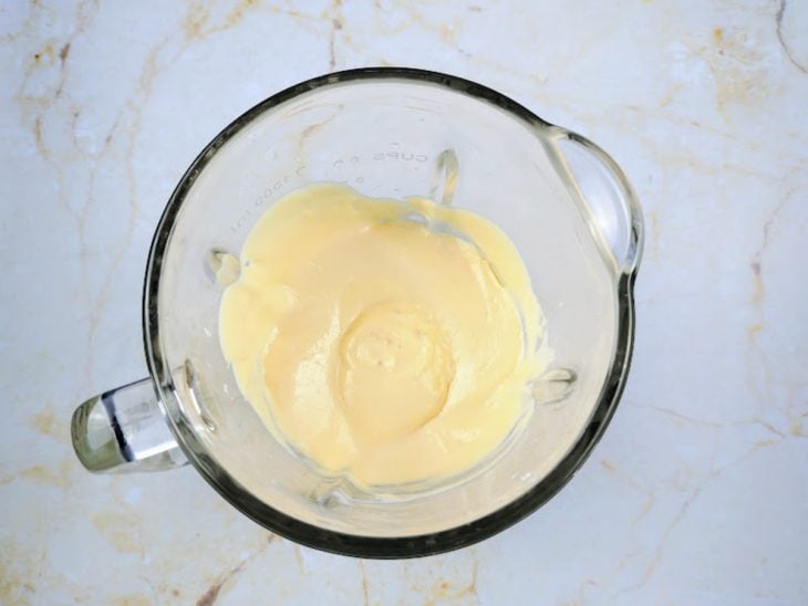 Um liquidificador contendo a mistura de creme de leite, suco em pó e leite condensado.