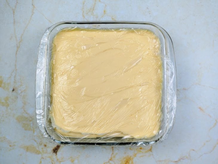 Uma travessa com a mistura da mousse coberta com plástico-filme.
