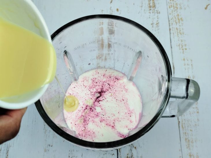 Um liquidificador com creme de leite, suco de uva e leite condensado.