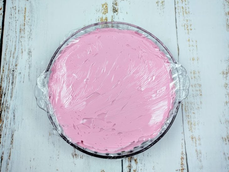 Uma travessa com a mousse de uva coberta com plástico-filme.