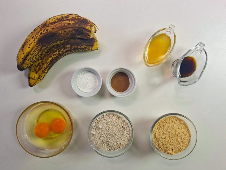 Ingredientes organizados na bancada com bananas, ovos e farinhas.